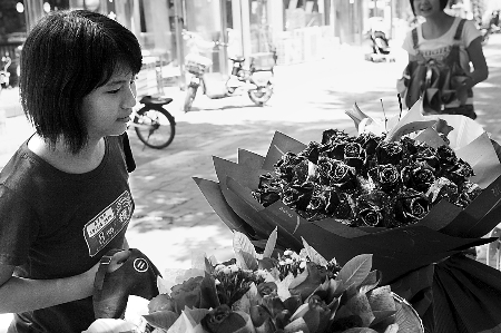 鄭州市農(nóng)業(yè)路一家花店擺放的玫瑰花吸引著一位過往女孩。
